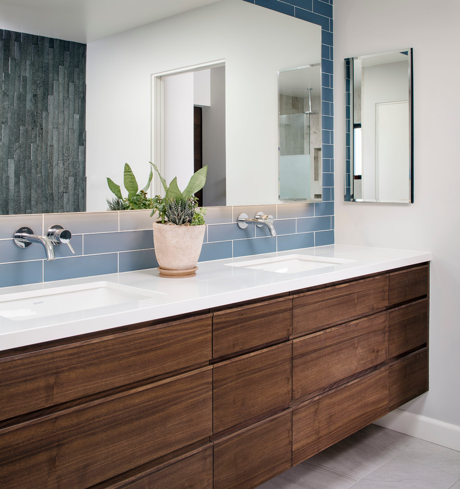 Пример оригинального дизайна: главная ванная комната среднего размера в современном стиле с плоскими фасадами, темными деревянными фасадами, столешницей из искусственного камня, синей плиткой, плиткой кабанчик, белыми стенами, полом из керамической плитки, врезной раковиной и отдельно стоящей ванной