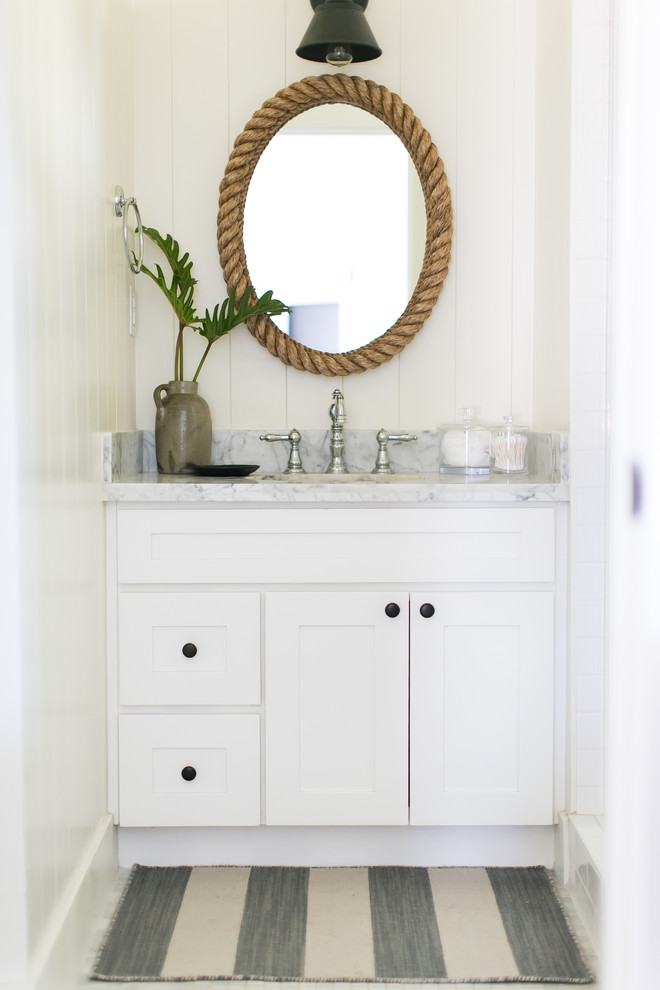 Foto på ett litet maritimt badrum, med skåp i shakerstil, vita skåp, vit kakel, vita väggar, marmorgolv, marmorbänkskiva och ett konsol handfat