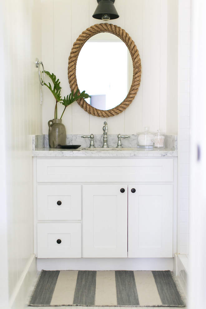 Idée de décoration pour une petite salle de bain marine avec un placard à porte shaker, des portes de placard blanches, un carrelage blanc, un mur blanc, un sol en marbre, un plan de toilette en marbre et un plan vasque.