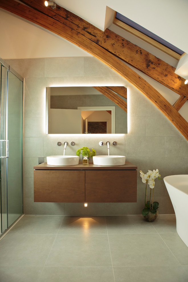 Inspiration for a rural ensuite bathroom in Other with flat-panel cabinets, medium wood cabinets, a freestanding bath, grey tiles, grey walls, a vessel sink, wooden worktops, grey floors, a sliding door and brown worktops.
