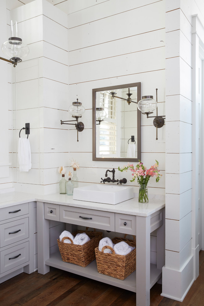 Maritimes Badezimmer mit Schrankfronten mit vertiefter Füllung, grauen Schränken, weißer Wandfarbe, braunem Holzboden, Aufsatzwaschbecken, braunem Boden und weißer Waschtischplatte