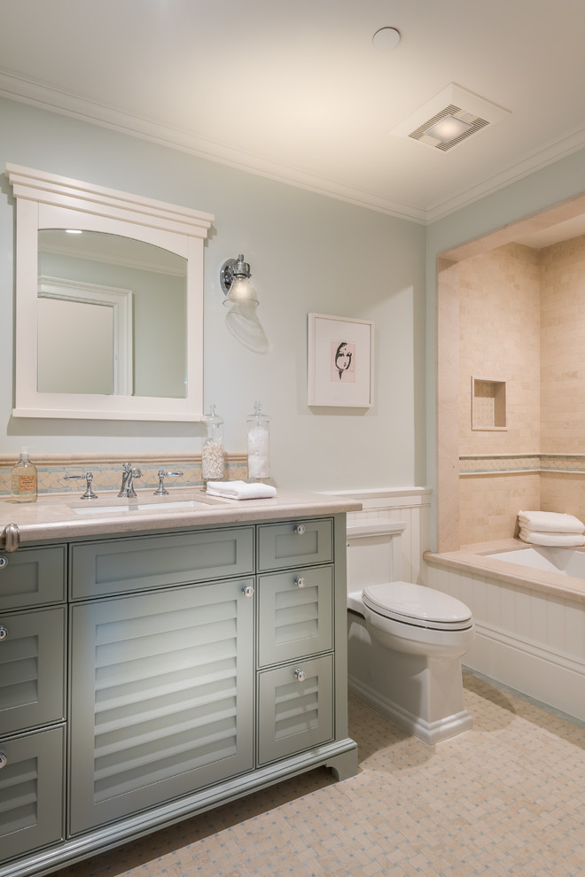 Идея дизайна: ванная комната в стиле неоклассика (современная классика) с фасадами с филенкой типа жалюзи, серыми фасадами, полновстраиваемой ванной, душем над ванной, бежевой плиткой, серыми стенами, полом из мозаичной плитки, врезной раковиной, бежевым полом и бежевой столешницей