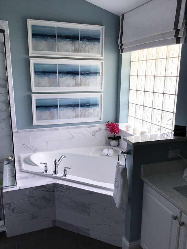 This is an example of a medium sized coastal ensuite bathroom in Orlando with raised-panel cabinets, white cabinets, a corner bath, an alcove shower, multi-coloured tiles, porcelain tiles, blue walls, porcelain flooring, a submerged sink, engineered stone worktops, grey floors, a hinged door, multi-coloured worktops, double sinks and a built in vanity unit.
