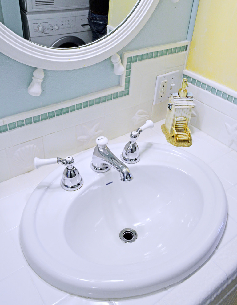 Immagine di una piccola stanza da bagno con doccia stile marinaro con ante con riquadro incassato, piastrelle bianche, piastrelle in ceramica, pareti blu, pavimento in vinile, lavabo da incasso e top piastrellato