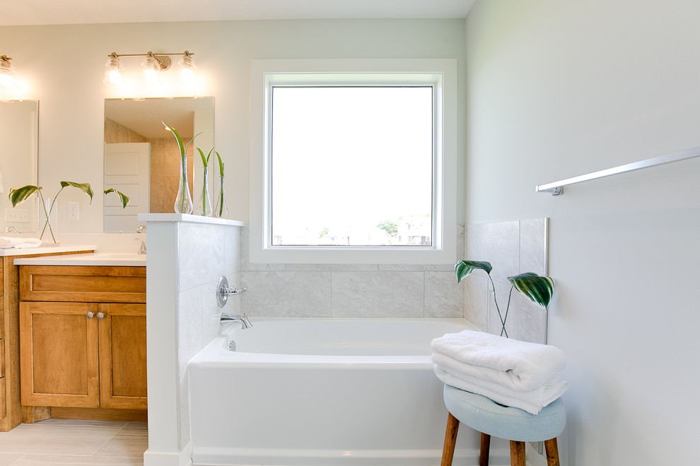 Photo of a medium sized beach style ensuite bathroom in Minneapolis with shaker cabinets, medium wood cabinets, grey tiles, ceramic tiles, ceramic flooring, engineered stone worktops, grey floors, a shower curtain, white worktops, a corner bath, grey walls and a submerged sink.