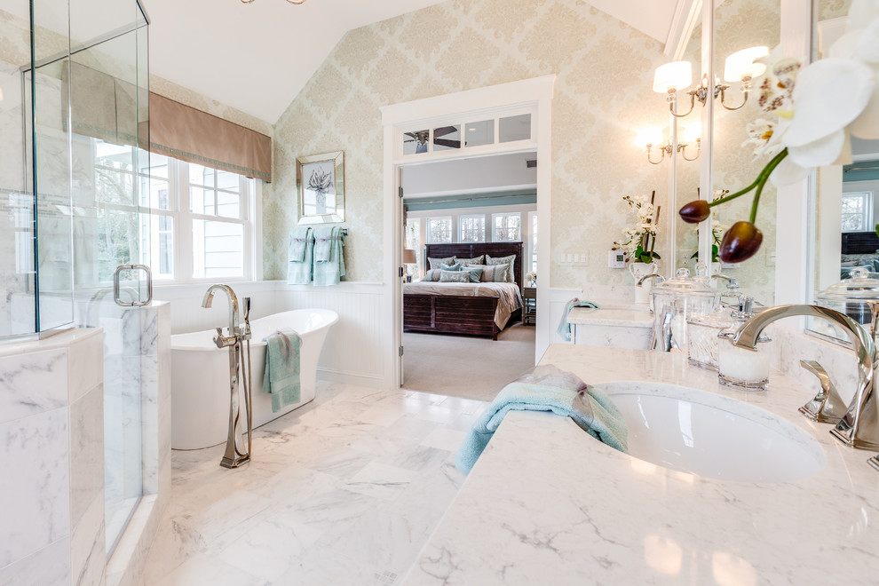 Cette image montre une salle de bain principale marine avec une baignoire indépendante, une douche d'angle, un mur beige, un lavabo encastré et une cabine de douche à porte battante.