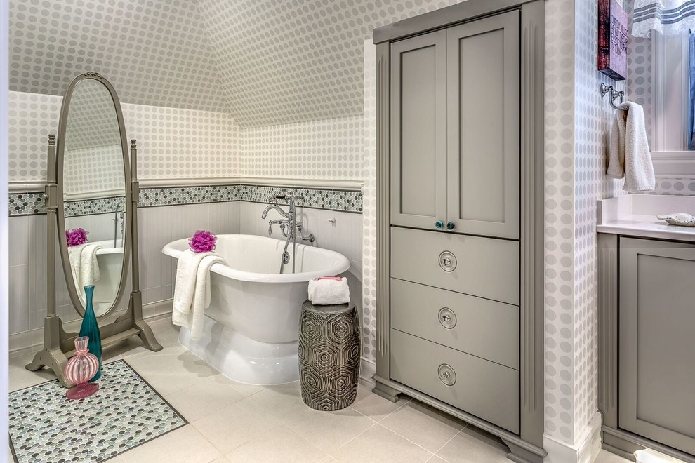 Idée de décoration pour une salle de bain principale tradition de taille moyenne avec un placard à porte shaker, des portes de placard grises, une baignoire indépendante, un carrelage blanc, des dalles de pierre, un mur gris, un sol en carrelage de céramique, un lavabo encastré, un plan de toilette en quartz et un sol gris.