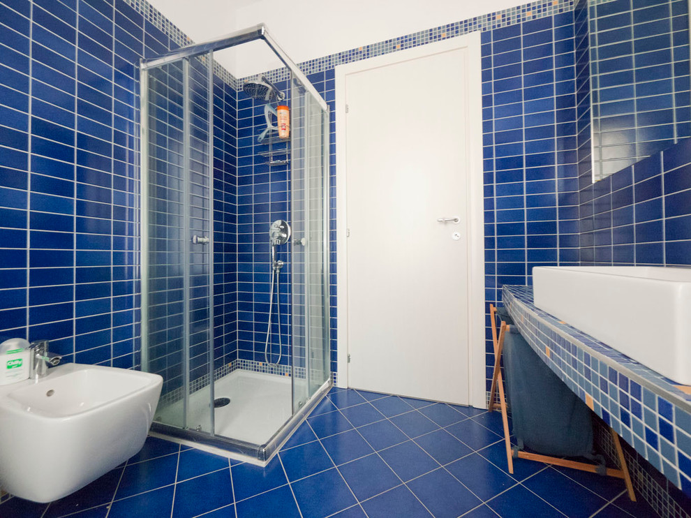 Inspiration for a small mediterranean ensuite bathroom in Milan with a console sink, tiled worktops, a corner shower, a wall mounted toilet, blue tiles, porcelain tiles, blue walls and porcelain flooring.