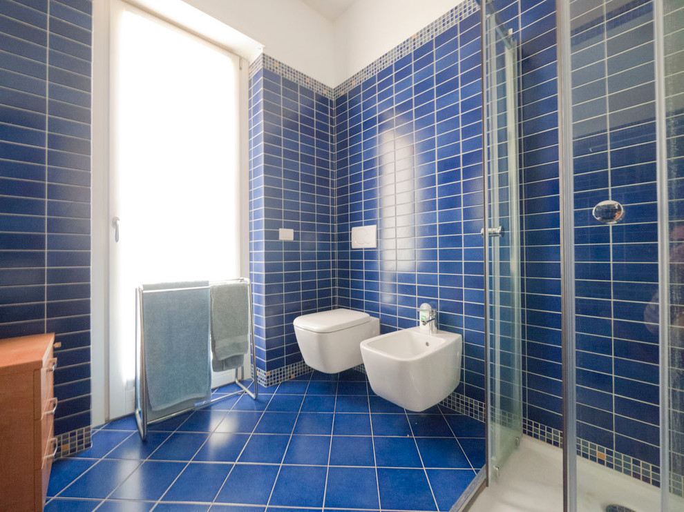 Réalisation d'une petite salle de bain principale méditerranéenne avec un plan vasque, une douche d'angle, WC suspendus, un carrelage bleu, des carreaux de porcelaine, un mur bleu et un sol en carrelage de porcelaine.