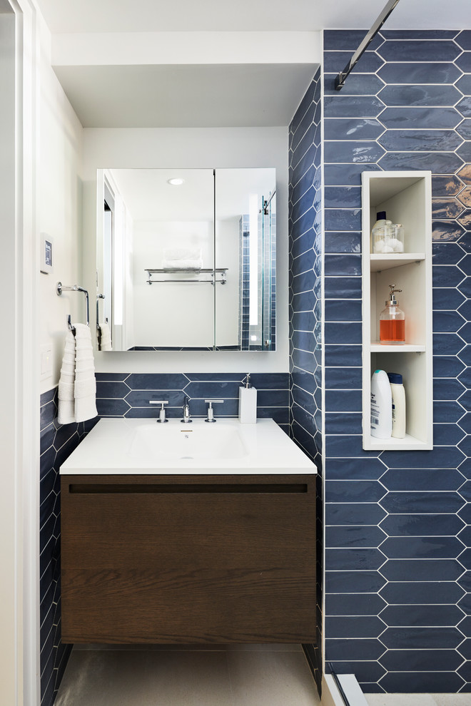 This is an example of a medium sized modern family bathroom in New York with ceramic tiles, blue walls, limestone flooring, a wall-mounted sink, beige floors and a sliding door.