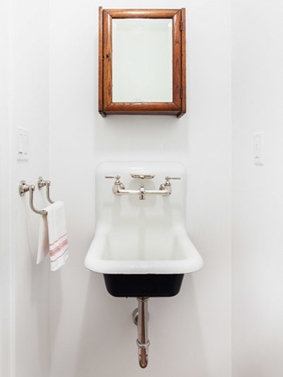 Kleines Modernes Badezimmer mit Trogwaschbecken, hellbraunen Holzschränken, Wandtoilette mit Spülkasten und braunem Holzboden in New York