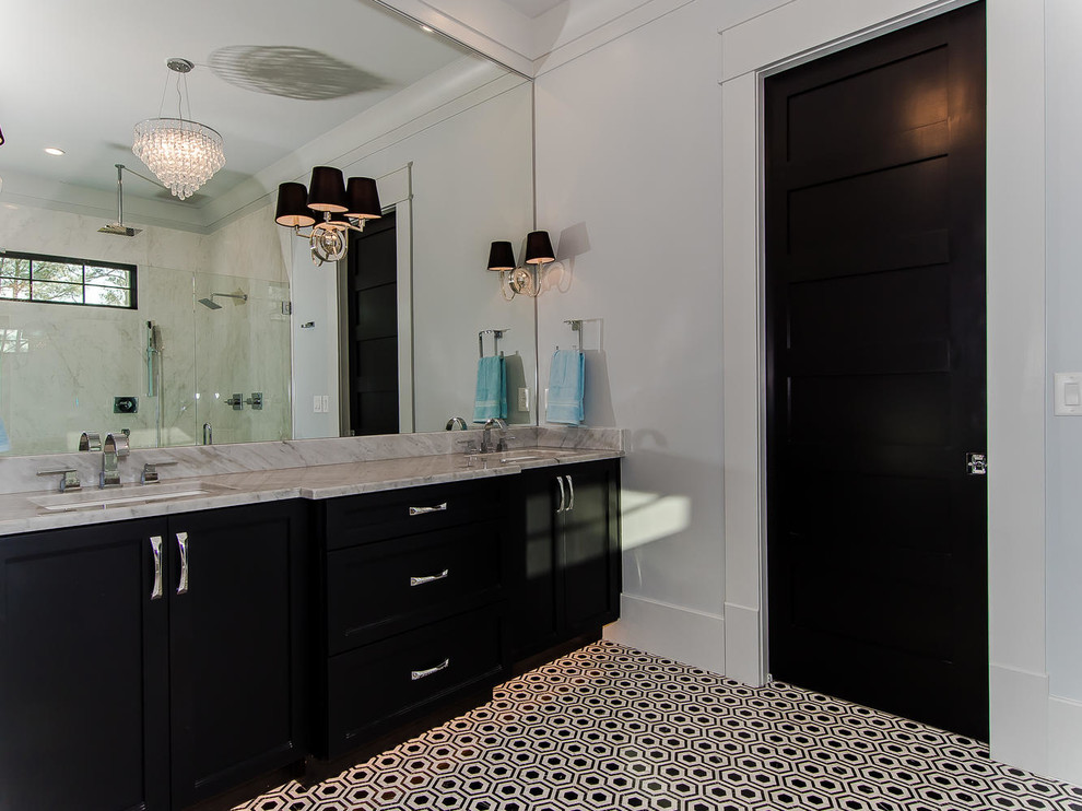 Example of a large transitional master gray tile, white tile and stone slab porcelain tile and black floor bathroom design in Raleigh with raised-panel cabinets, white cabinets, a one-piece toilet, white walls, a drop-in sink and marble countertops