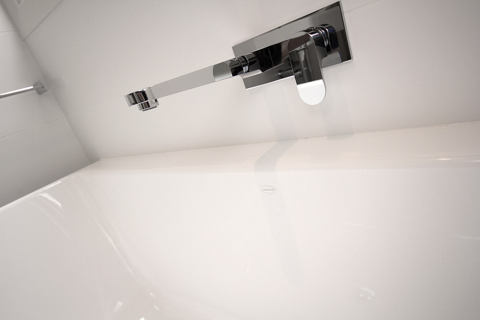 Bild på ett mellanstort funkis en-suite badrum, med ett väggmonterat handfat, ett fristående badkar, en öppen dusch, en toalettstol med hel cisternkåpa, vit kakel, porslinskakel, vita väggar och klinkergolv i porslin