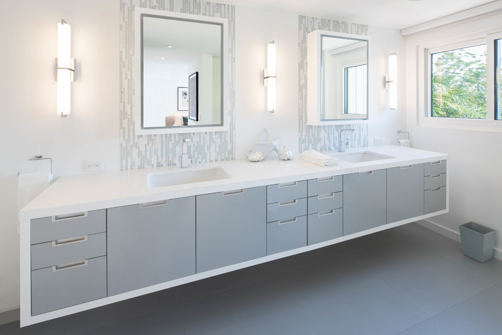 Large modern ensuite bathroom in Miami with a submerged sink, flat-panel cabinets, grey cabinets, engineered stone worktops, a wall mounted toilet, grey tiles, glass tiles, white walls and porcelain flooring.
