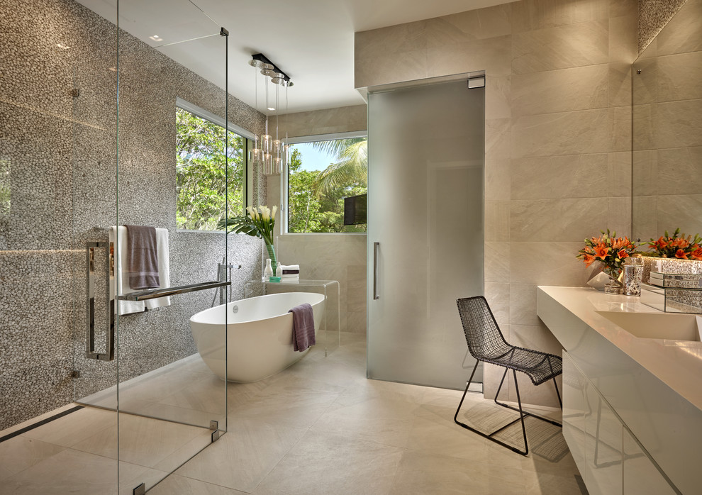 Diseño de cuarto de baño actual de tamaño medio con lavabo integrado, bañera exenta, armarios con paneles lisos, puertas de armario blancas y baldosas y/o azulejos grises