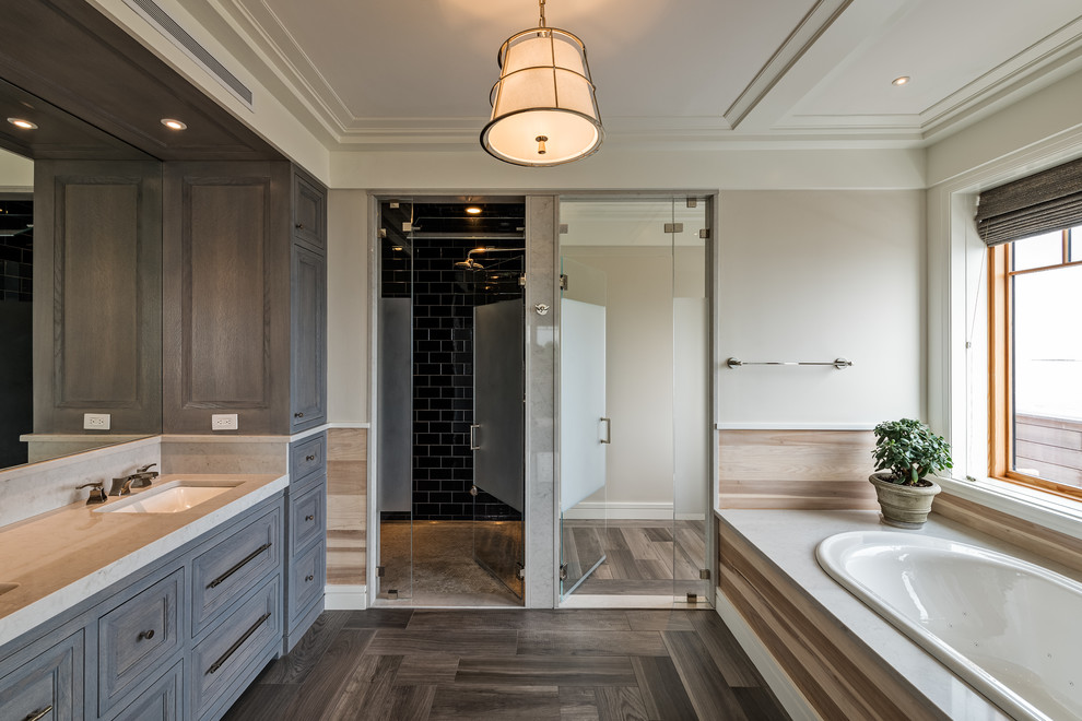 Photo of a beach style bathroom in Boston with recessed-panel cabinets, grey cabinets, a built-in bath, beige walls, a submerged sink, brown floors and grey worktops.