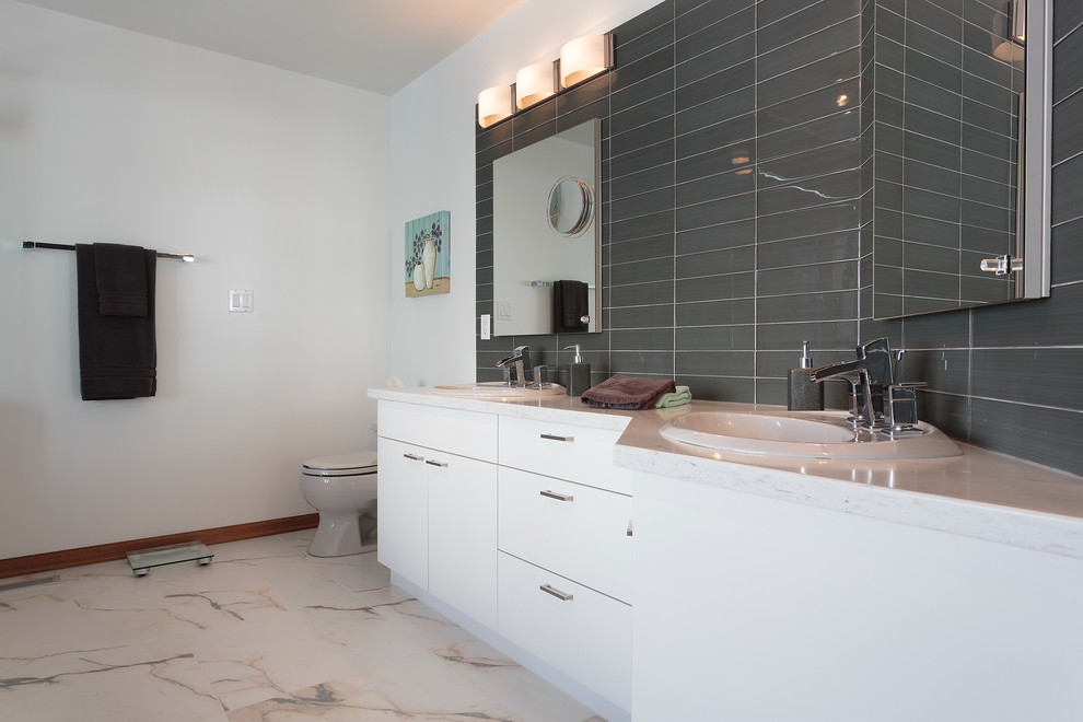 Inspiration for a large classic ensuite bathroom in Other with flat-panel cabinets, white cabinets, an alcove bath, a corner shower, a two-piece toilet, black tiles, grey tiles, glass tiles, white walls, marble flooring, a built-in sink and solid surface worktops.