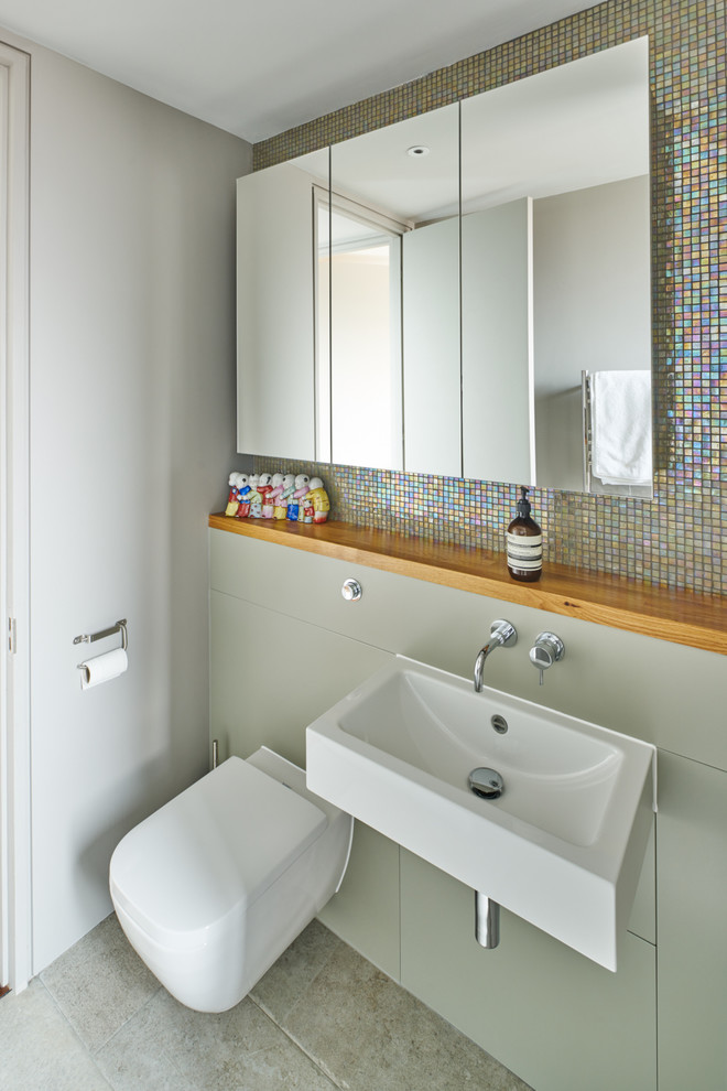 This is an example of a large family bathroom in London with flat-panel cabinets, a double shower, a wall mounted toilet, mosaic tiles, white walls, a wall-mounted sink, wooden worktops, beige cabinets, multi-coloured tiles and ceramic flooring.