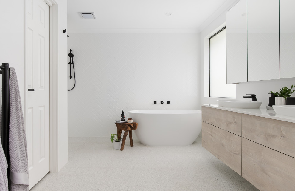 Inredning av ett nordiskt mellanstort vit vitt en-suite badrum, med skåp i ljust trä, ett fristående badkar, vit kakel, cementkakel, vita väggar, klinkergolv i keramik, ett fristående handfat, bänkskiva i kvarts, grått golv, med dusch som är öppen, släta luckor och en kantlös dusch