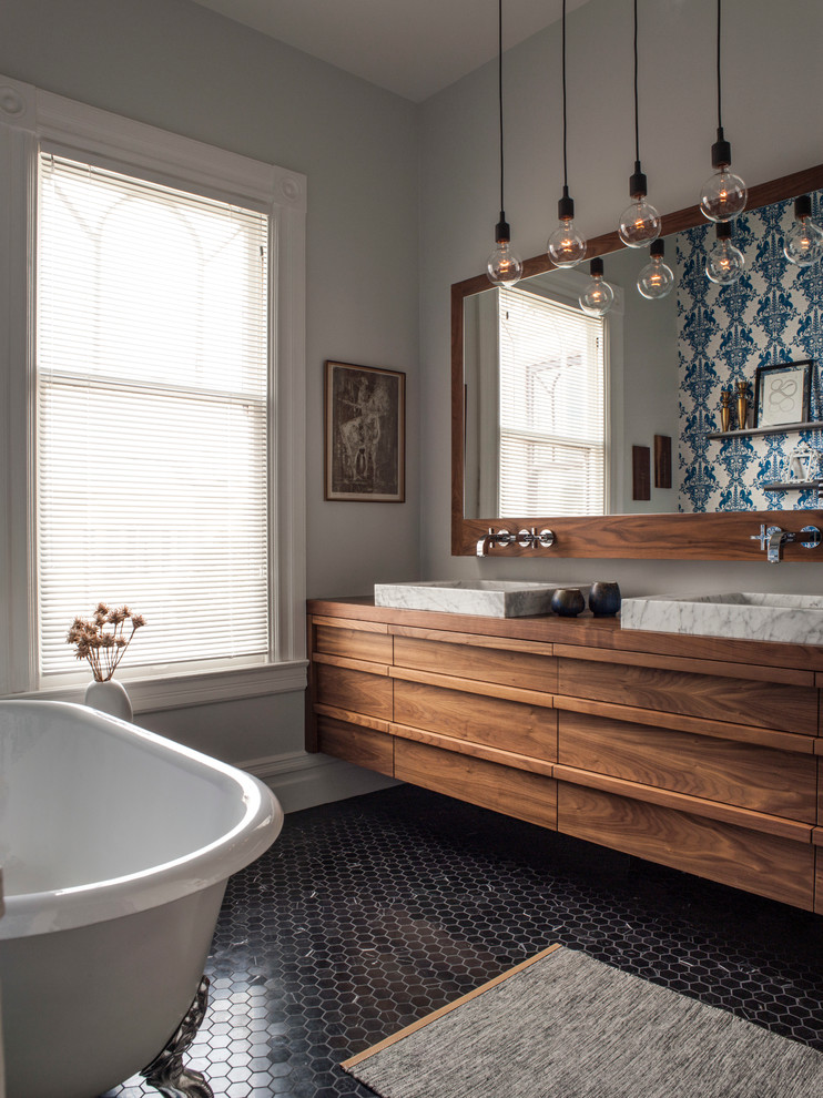 Réalisation d'une salle de bain design en bois foncé avec une vasque, un plan de toilette en bois, une baignoire sur pieds, un mur gris, un sol en carrelage de terre cuite et un plan de toilette marron.