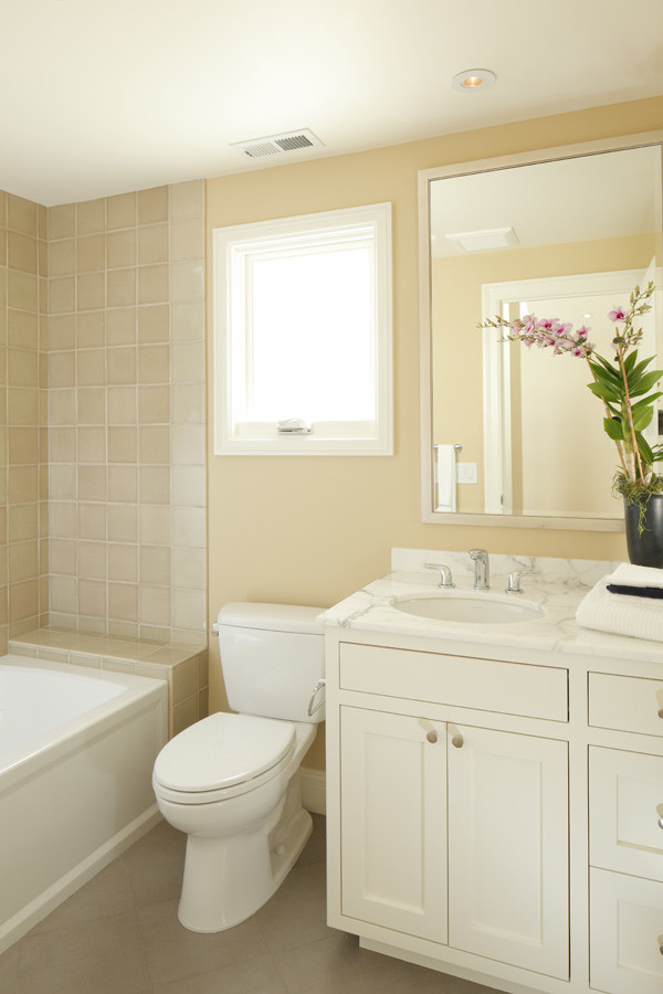 На фото: ванная комната среднего размера в стиле неоклассика (современная классика) с врезной раковиной, фасадами с утопленной филенкой, белыми фасадами, мраморной столешницей, накладной ванной, душем над ванной, раздельным унитазом, зеленой плиткой, керамогранитной плиткой, желтыми стенами, полом из керамогранита и душевой кабиной с