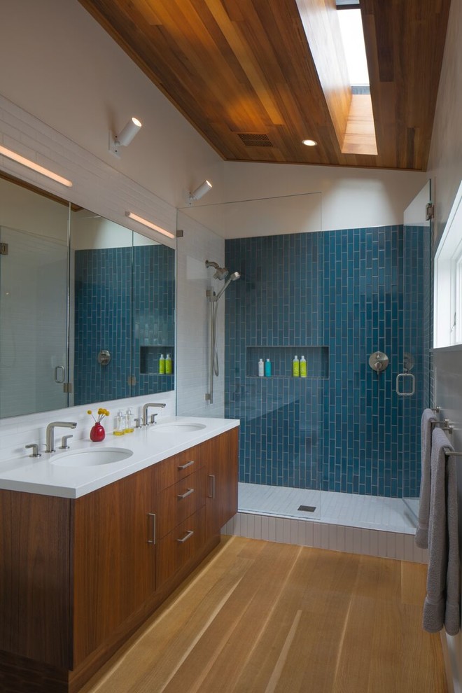 Idee per una stanza da bagno contemporanea di medie dimensioni con ante lisce, ante in legno scuro, doccia alcova, piastrelle blu, lavabo sottopiano e pavimento in legno massello medio