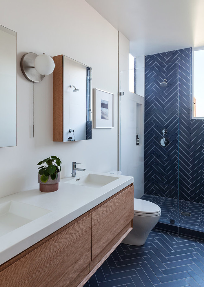 Cette photo montre une salle de bain tendance en bois brun avec un placard à porte plane, une douche d'angle, un mur blanc, un lavabo intégré, aucune cabine, un plan de toilette blanc, un carrelage bleu et un sol bleu.