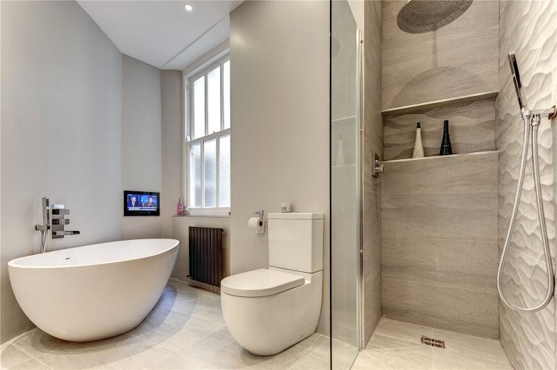 Großes Modernes Badezimmer mit weißen Schränken, Mineralwerkstoff-Waschtisch, freistehender Badewanne, offener Dusche, Wandtoilette mit Spülkasten, grauen Fliesen, Keramikfliesen, grauer Wandfarbe und Porzellan-Bodenfliesen in London