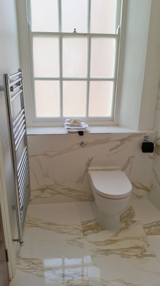 Bild på ett stort funkis badrum, med ett avlångt handfat, vita skåp, bänkskiva i akrylsten, ett fristående badkar, grå kakel, keramikplattor, grå väggar och klinkergolv i porslin