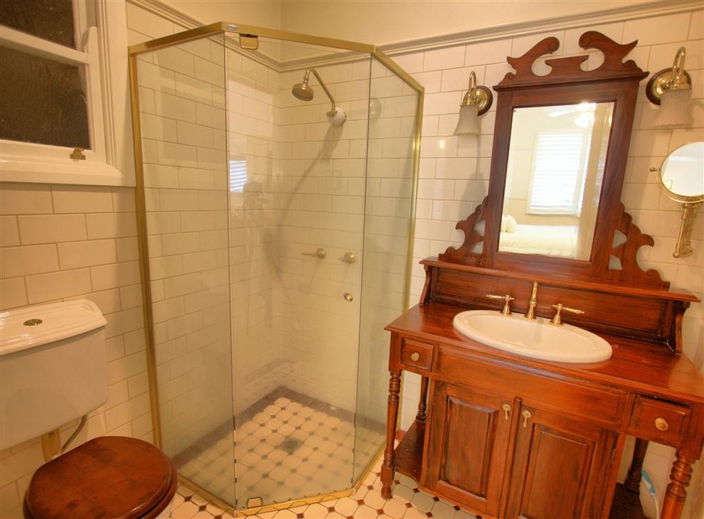 Exempel på ett klassiskt badrum, med ett nedsänkt handfat, bruna skåp, marmorbänkskiva, ett badkar med tassar, en hörndusch, en toalettstol med separat cisternkåpa och keramikplattor