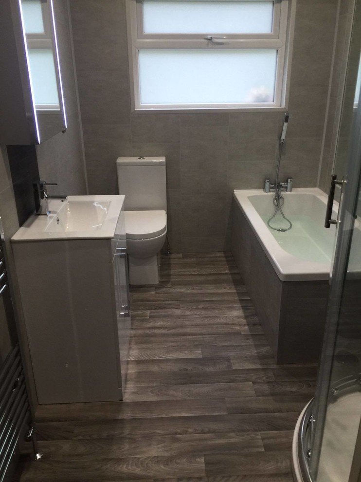 他の地域にあるコンテンポラリースタイルのおしゃれな浴室 (白いキャビネット、コーナー設置型シャワー、分離型トイレ、グレーのタイル、グレーの壁、クッションフロア) の写真