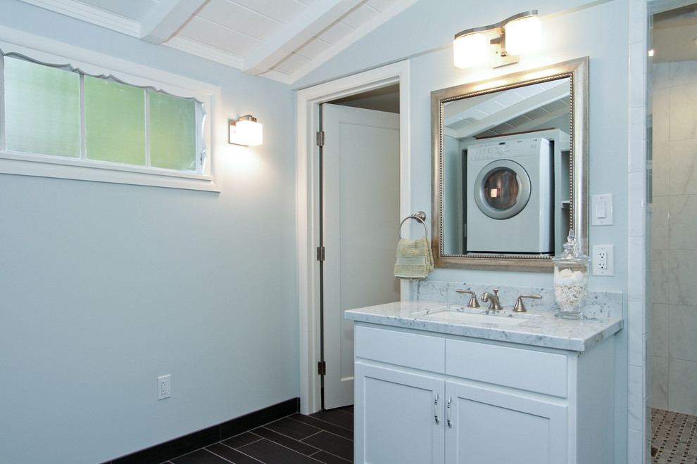 Réalisation d'une salle de bain marine de taille moyenne avec un lavabo encastré, des portes de placard blanches, un plan de toilette en marbre et un carrelage gris.