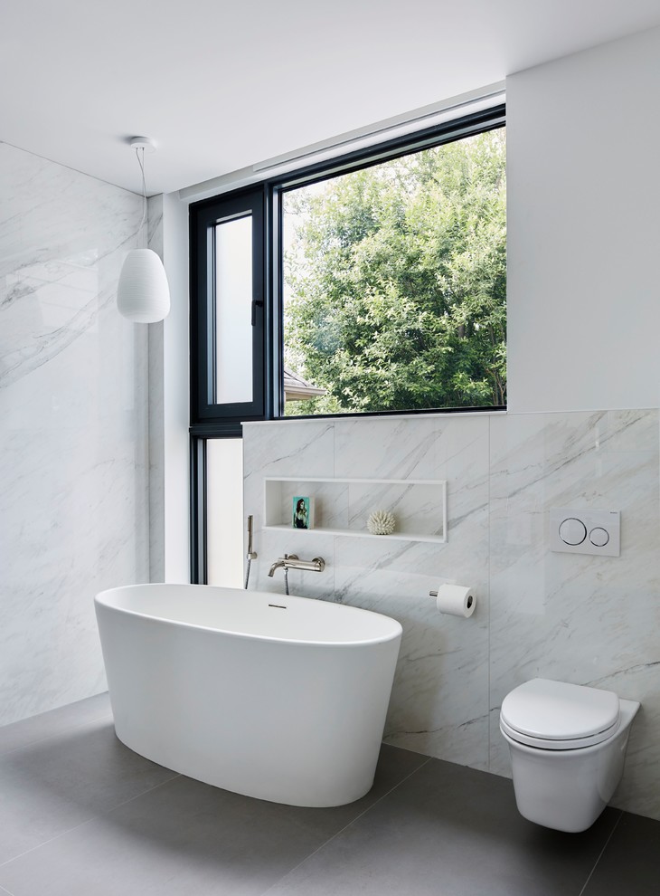 Immagine di una stanza da bagno padronale design con vasca freestanding, WC sospeso, pareti bianche, pavimento grigio, zona vasca/doccia separata, piastrelle grigie, piastrelle bianche e piastrelle di marmo