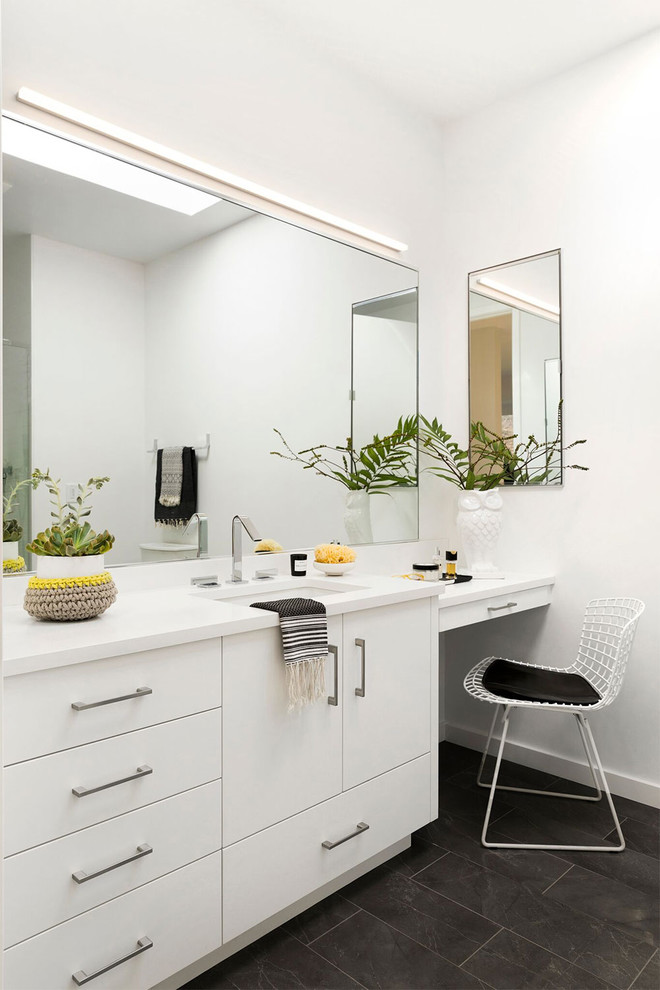 Réalisation d'une salle de bain design avec un placard à porte plane, des portes de placard blanches, un mur blanc, un lavabo encastré et un sol noir.