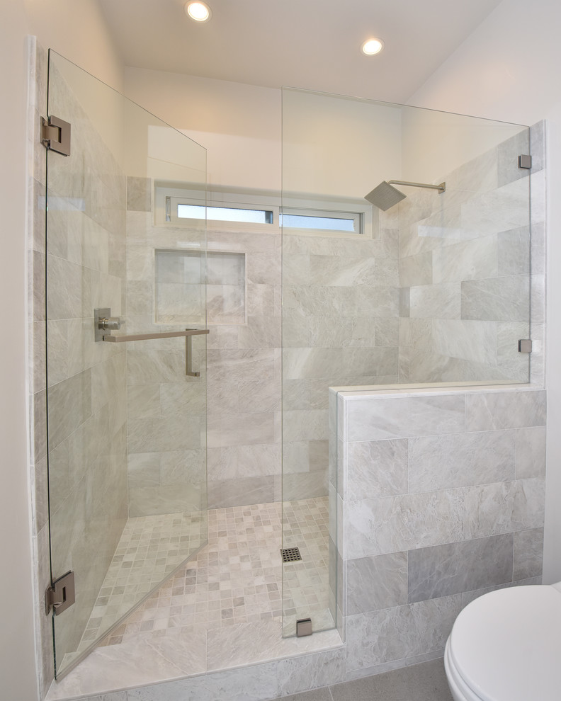 Idéer för att renovera ett mellanstort funkis badrum med dusch, med släta luckor, vita skåp, en dusch i en alkov, en toalettstol med hel cisternkåpa, vit kakel, marmorkakel, vita väggar, bänkskiva i akrylsten, dusch med gångjärnsdörr, klinkergolv i porslin och grått golv