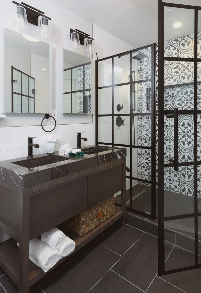 Inspiration for a medium sized modern ensuite bathroom in New York with freestanding cabinets, dark wood cabinets, white tiles, metro tiles, soapstone worktops, black worktops, an alcove shower, white walls, porcelain flooring, an integrated sink, black floors and a hinged door.