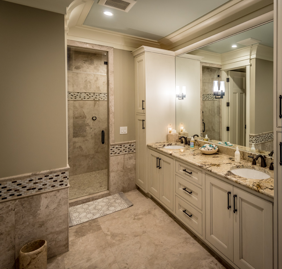 Design ideas for a large classic ensuite bathroom in Charleston with beige cabinets, an alcove shower, beige tiles, limestone tiles, beige walls, limestone flooring, a submerged sink, beige floors, a hinged door, a freestanding bath, a one-piece toilet, recessed-panel cabinets and granite worktops.
