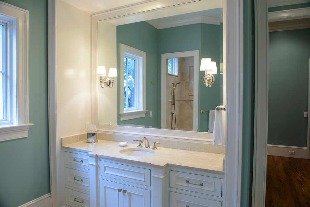 Idée de décoration pour une salle de bain tradition avec un lavabo encastré, un plan de toilette en marbre, une baignoire posée, un carrelage beige, un mur bleu et un sol en marbre.