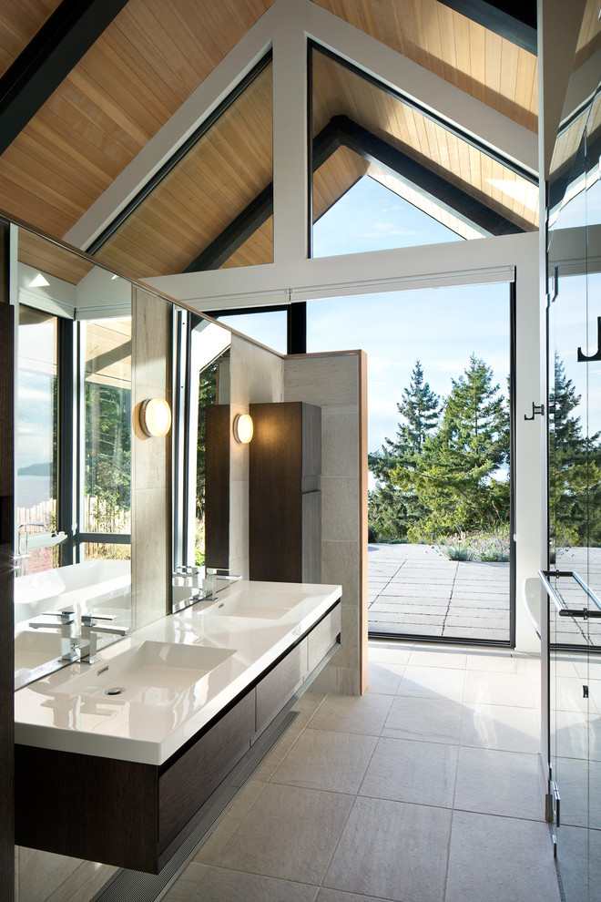 Inspiration for a medium sized contemporary ensuite bathroom in Vancouver with a submerged sink, flat-panel cabinets, dark wood cabinets, engineered stone worktops, a freestanding bath, a double shower, a wall mounted toilet, beige tiles, porcelain tiles, white walls and porcelain flooring.