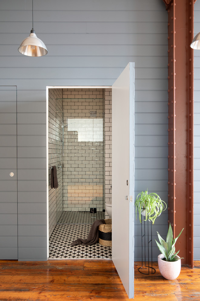 Bild på ett litet funkis badrum, med en dusch i en alkov, en toalettstol med hel cisternkåpa, vit kakel, keramikplattor, vita väggar, mosaikgolv, svart golv och dusch med gångjärnsdörr