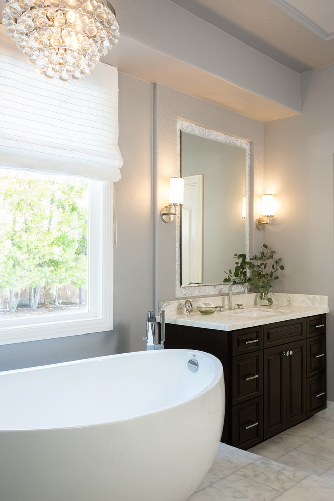 This is an example of a large traditional ensuite bathroom in San Diego with raised-panel cabinets, dark wood cabinets, a freestanding bath, an alcove shower, a one-piece toilet, white tiles, stone tiles, grey walls, marble flooring, a submerged sink and marble worktops.