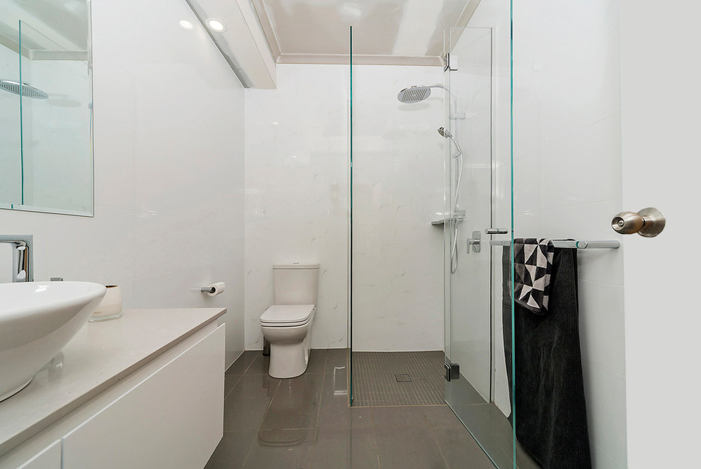 This is an example of a small contemporary bathroom in Adelaide with flat-panel cabinets, a built-in shower, a two-piece toilet, white tiles, porcelain tiles, white walls, porcelain flooring, a vessel sink and granite worktops.