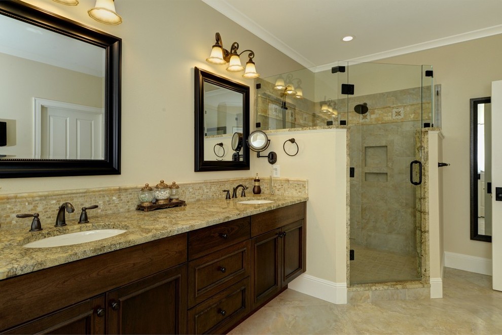 Inredning av ett klassiskt mellanstort en-suite badrum, med ett undermonterad handfat, luckor med profilerade fronter, skåp i mörkt trä, marmorbänkskiva, ett hörnbadkar, en dusch i en alkov, beige kakel, mosaik, beige väggar och marmorgolv