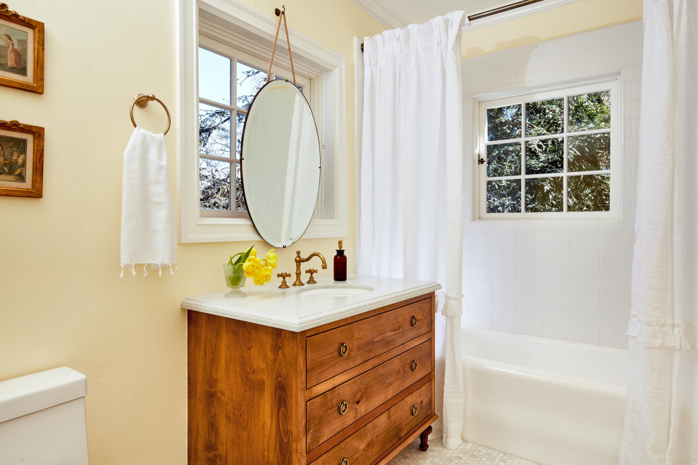 サンフランシスコにあるラグジュアリーな中くらいなトラディショナルスタイルのおしゃれな浴室 (フラットパネル扉のキャビネット、中間色木目調キャビネット、アルコーブ型浴槽、シャワー付き浴槽	、白いタイル、黄色い壁、モザイクタイル、アンダーカウンター洗面器、白い床、シャワーカーテン、白い洗面カウンター、洗面台1つ、独立型洗面台、セラミックタイル、白い天井) の写真