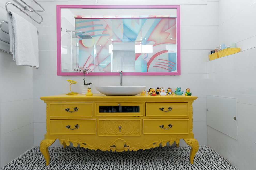 На фото: ванная комната в стиле фьюжн с желтыми фасадами, белой плиткой, белыми стенами, настольной раковиной, столешницей из дерева, разноцветным полом, желтой столешницей и фасадами с утопленной филенкой