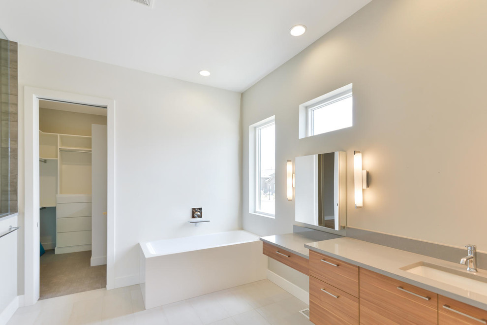 Стильный дизайн: большая главная ванная комната в современном стиле с плоскими фасадами, светлыми деревянными фасадами, серыми стенами, полом из керамической плитки, врезной раковиной, столешницей из искусственного кварца, душем в нише, отдельно стоящей ванной и бежевым полом - последний тренд