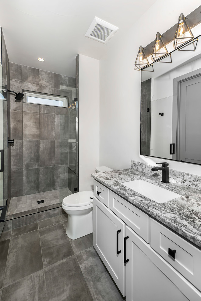 Esempio di una stanza da bagno padronale design con ante bianche, piastrelle grigie, pareti bianche, pavimento grigio e top grigio