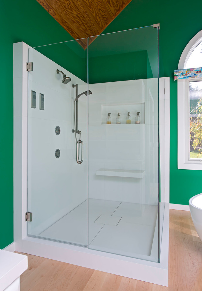 Cette photo montre une grande salle de bain principale bord de mer avec un placard à porte affleurante, des portes de placard blanches, une baignoire indépendante, une douche d'angle, un plan de toilette en onyx, des dalles de pierre, un mur vert, parquet clair et un lavabo encastré.
