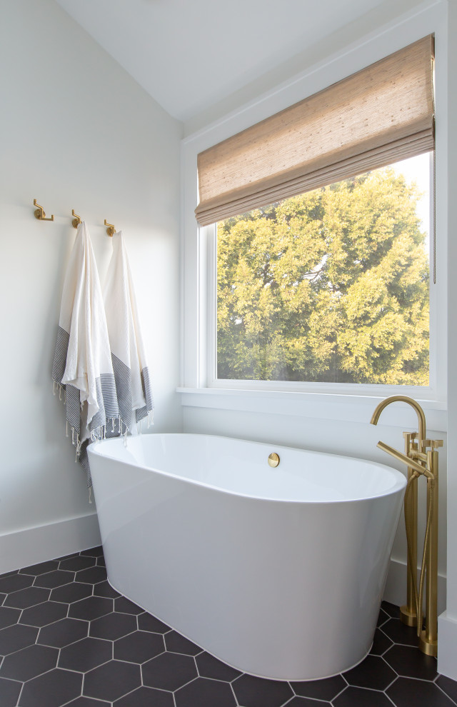 Diseño de cuarto de baño principal y abovedado costero con bañera exenta, paredes blancas y suelo negro