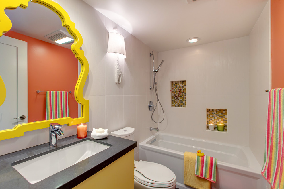 На фото: детская ванная комната в современном стиле с врезной раковиной, плоскими фасадами, желтыми фасадами, ванной в нише, душем над ванной, белой плиткой и оранжевыми стенами